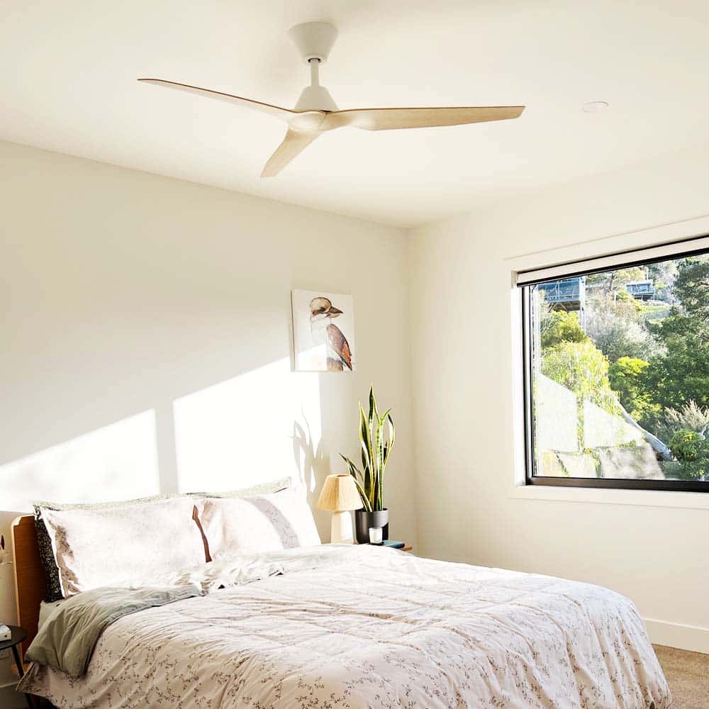 White and Beechwood Fanco Infinity-iD DC ceiling fan installed in a bright modern Australian bedroom with natural light.